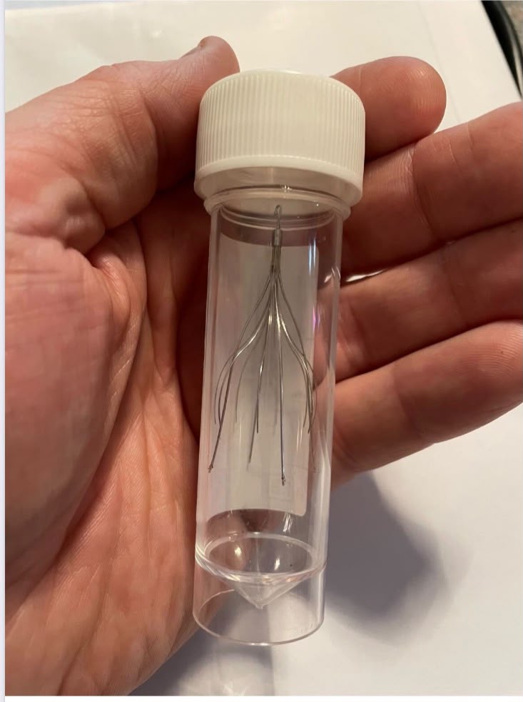 An IVC filter device held in a small clear vial, showing its wire legs designed to catch blood clots